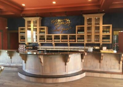 Wine tasting room with a wooden bar and wine bottles on display.