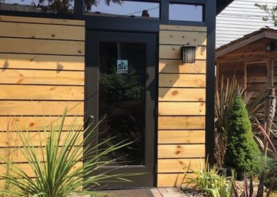 Modern wooden facade with a glass door and landscaped garden path.