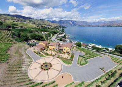 Aerial view of a lakeside community with vineyards, housing, and a roundabout.
