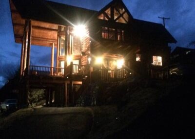 Illuminated house at dusk with lights glowing against a twilight sky.