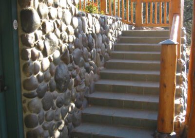 Stone wall and staircase with wooden railing leading to a door.