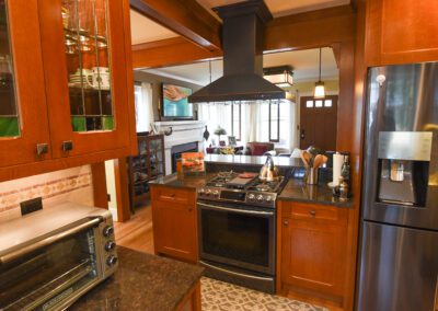 A modern kitchen with stainless steel appliances, wooden cabinets, and a view into an adjoining room.